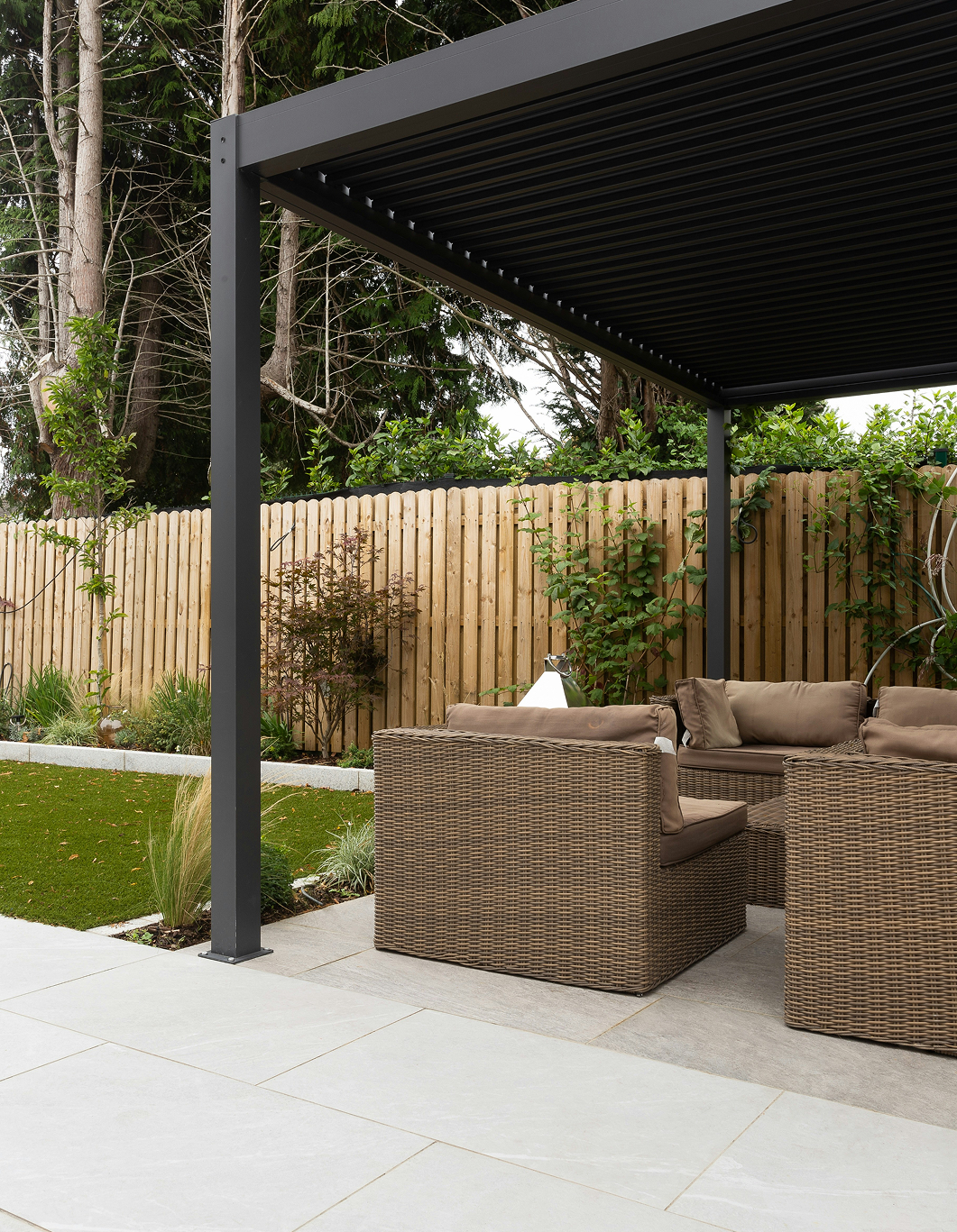 A patio area with wicker furniture under a pergola