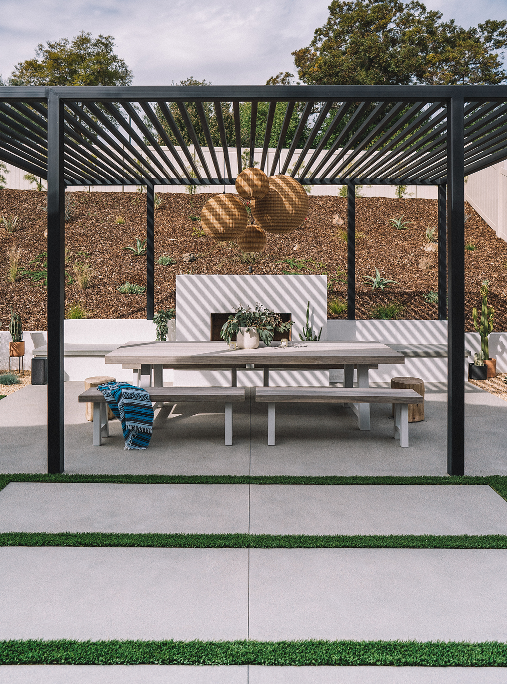 A patio with a table and benches under a pergola