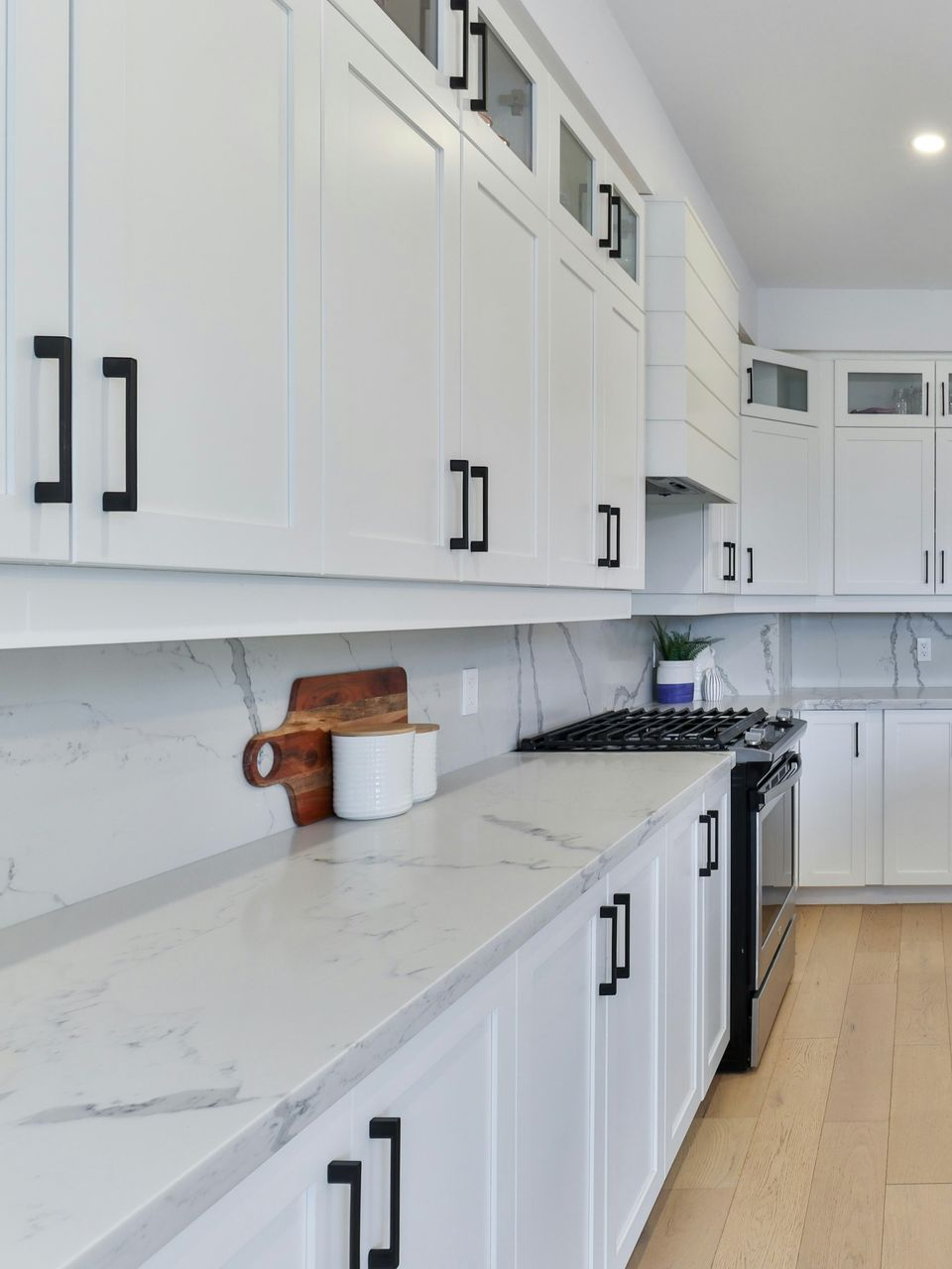 A kitchen with white cabinets and a wooden counter top.