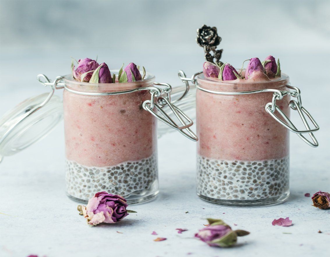 Deux pots remplis d'un smoothie rose et de graines de chia.