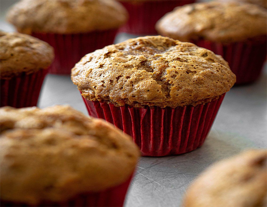 Un tas de muffins aux emballages rouges sont posés sur une table.