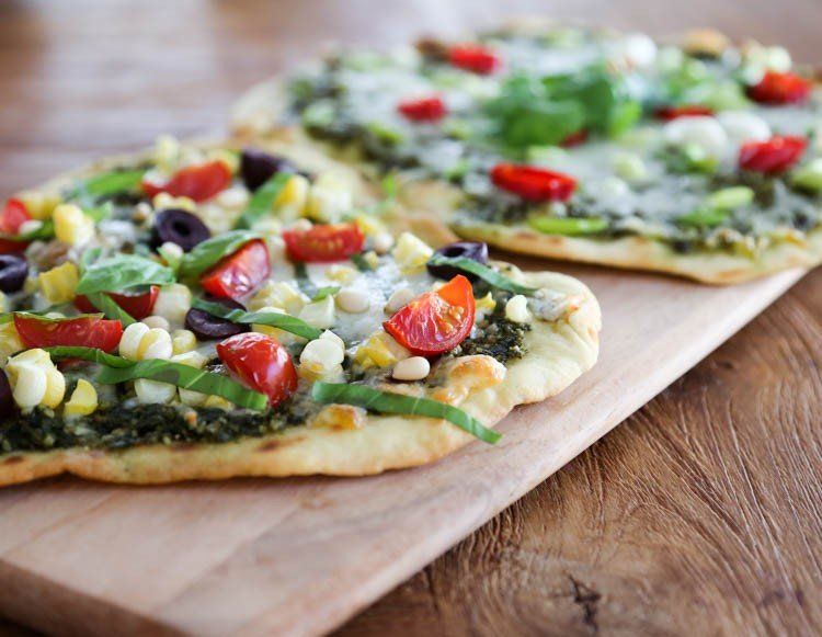 Deux pizzas sont posées sur une planche à découper en bois.