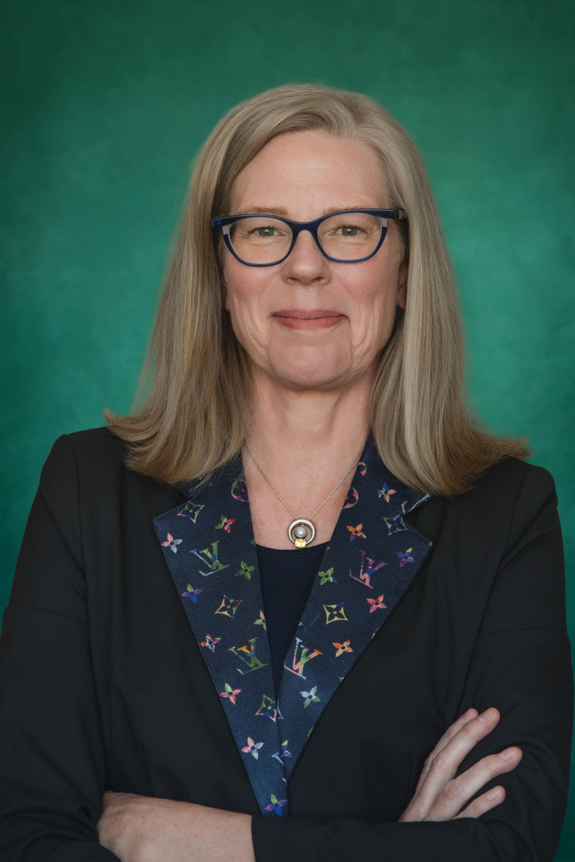 A woman wearing glasses and a blue jacket is sitting in a car. sloan johnson