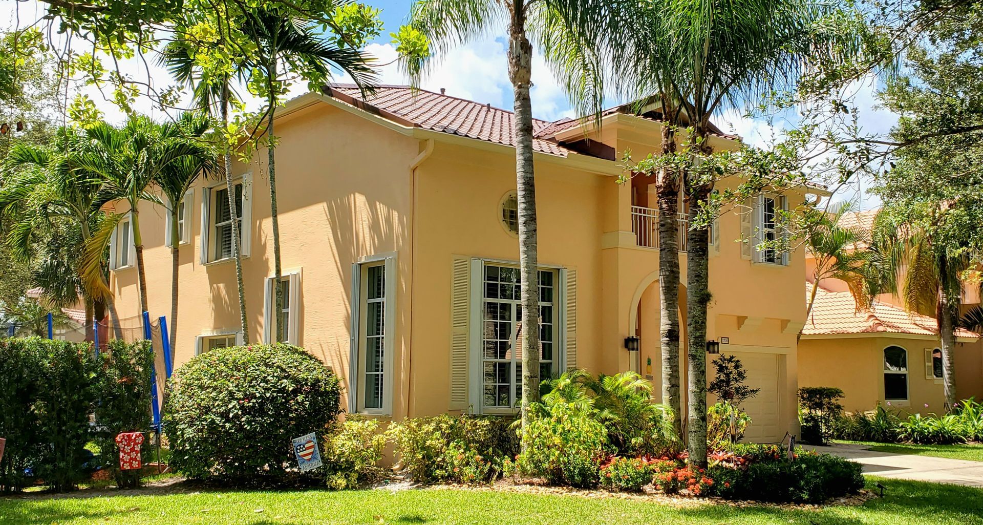 A large house with a lot of windows is surrounded by trees and bushes.