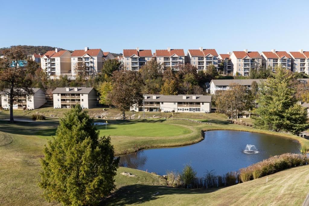 A lake with a fountain in the middle of it in front of a row of houses.