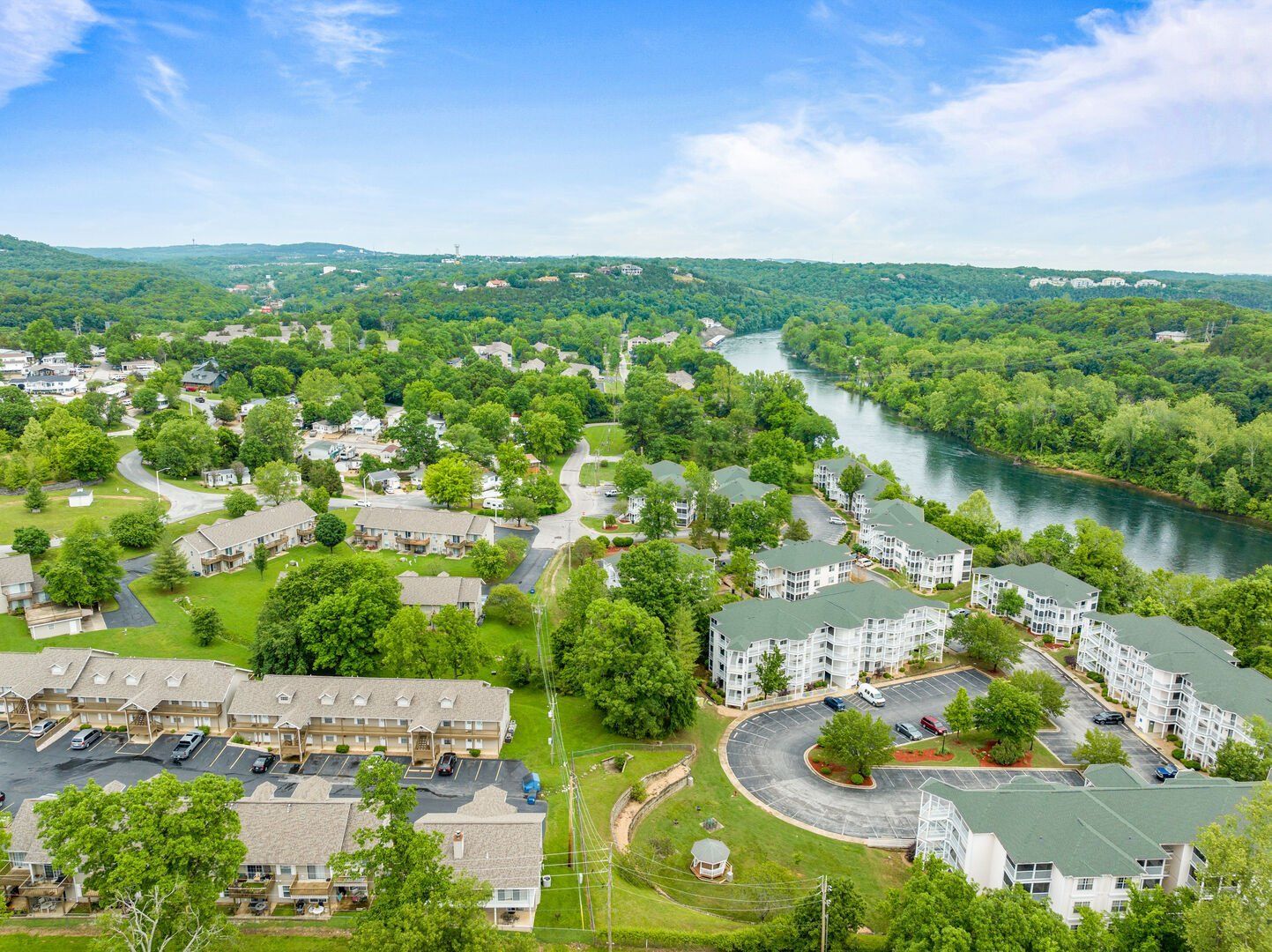 An aerial view of a residential area surrounded by trees and a river.