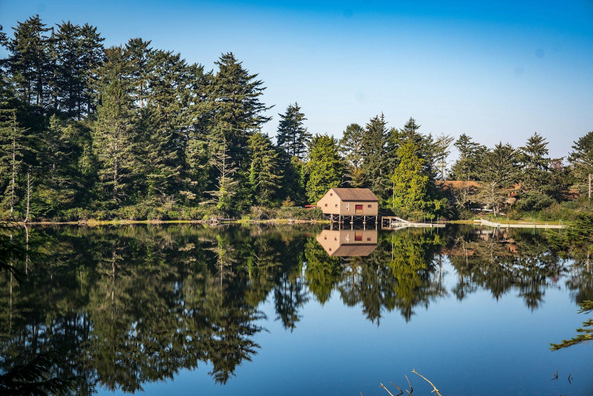A small house sits on a small island in the middle of a lake surrounded by trees.