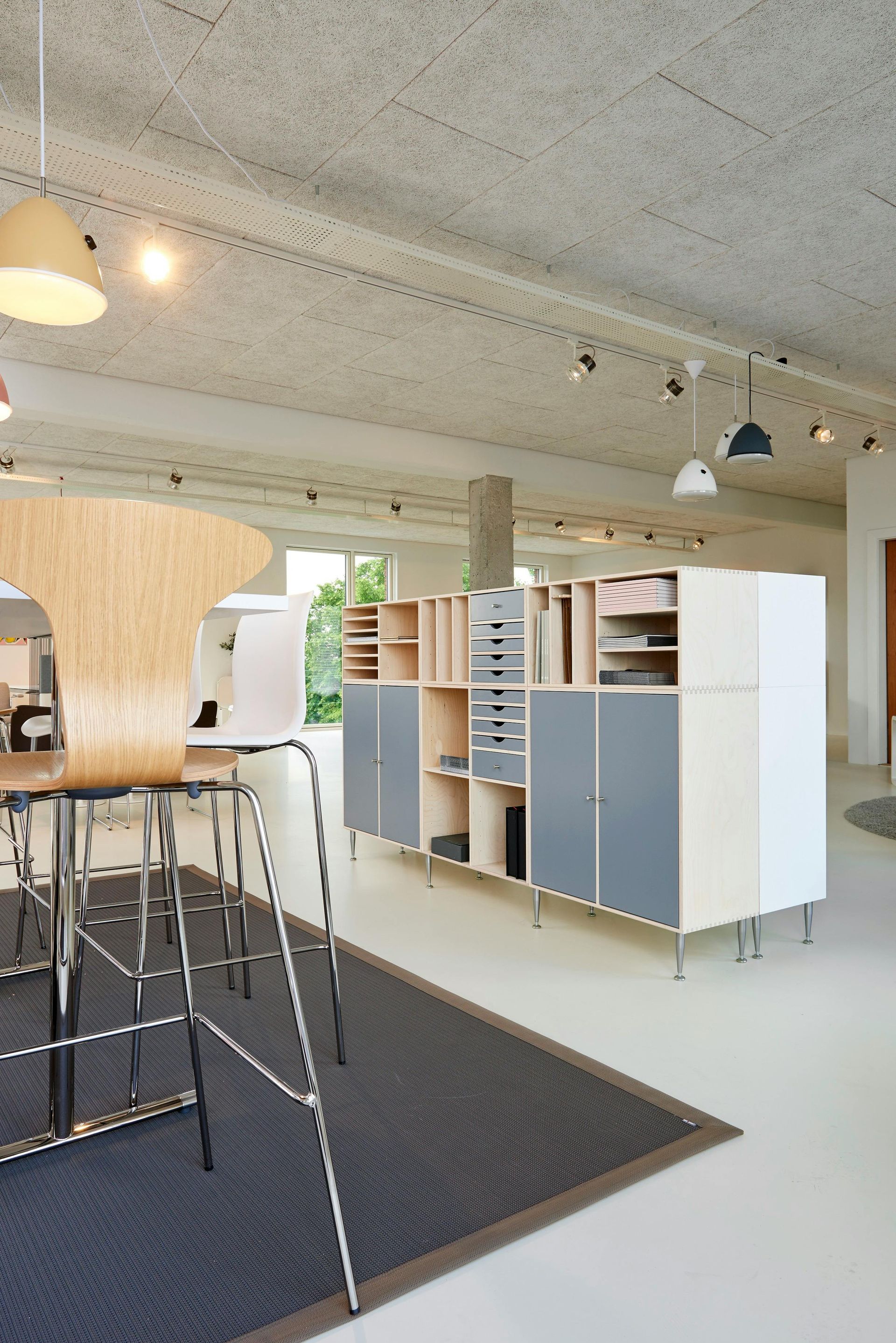 Modern office interior with modular storage, rugs, pendant lights, and a seating area.