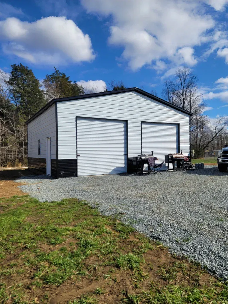 A white garage with two garage doors and a truck parked in front of it.