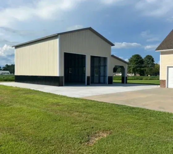 A garage with a large door is sitting in the middle of a lush green field.