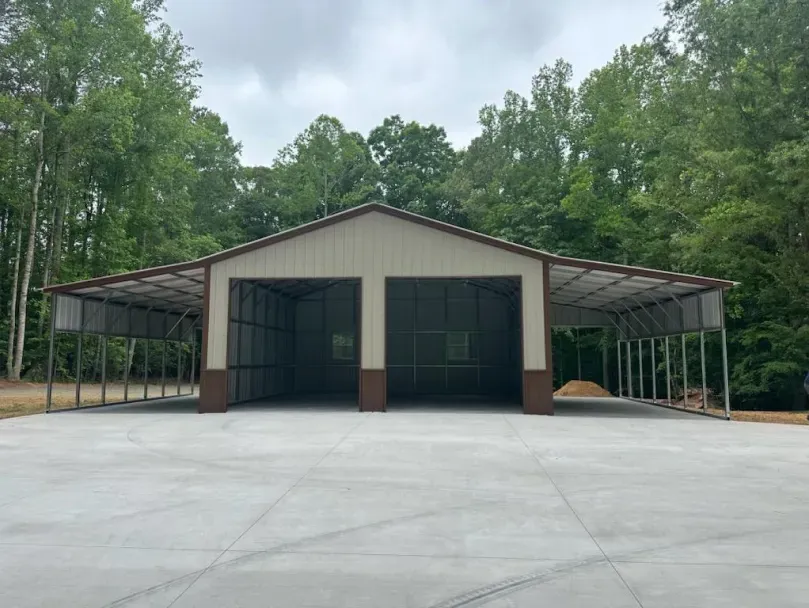 A large metal building with a concrete driveway and trees in the background