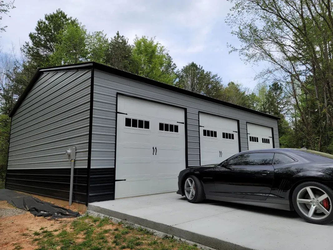 A black car is parked in front of a garage.