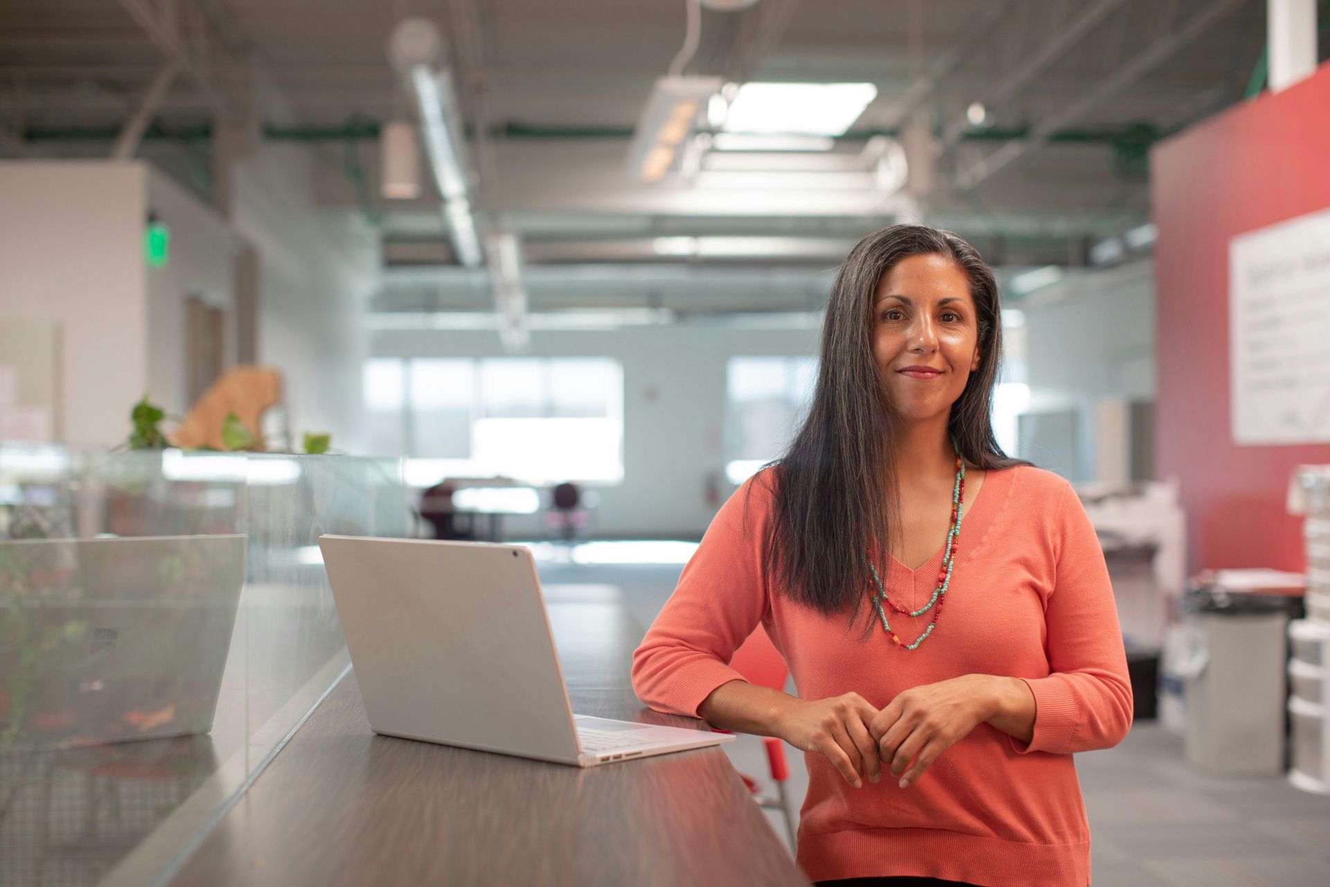A woman is sitting at a desk in front of a laptop computer.