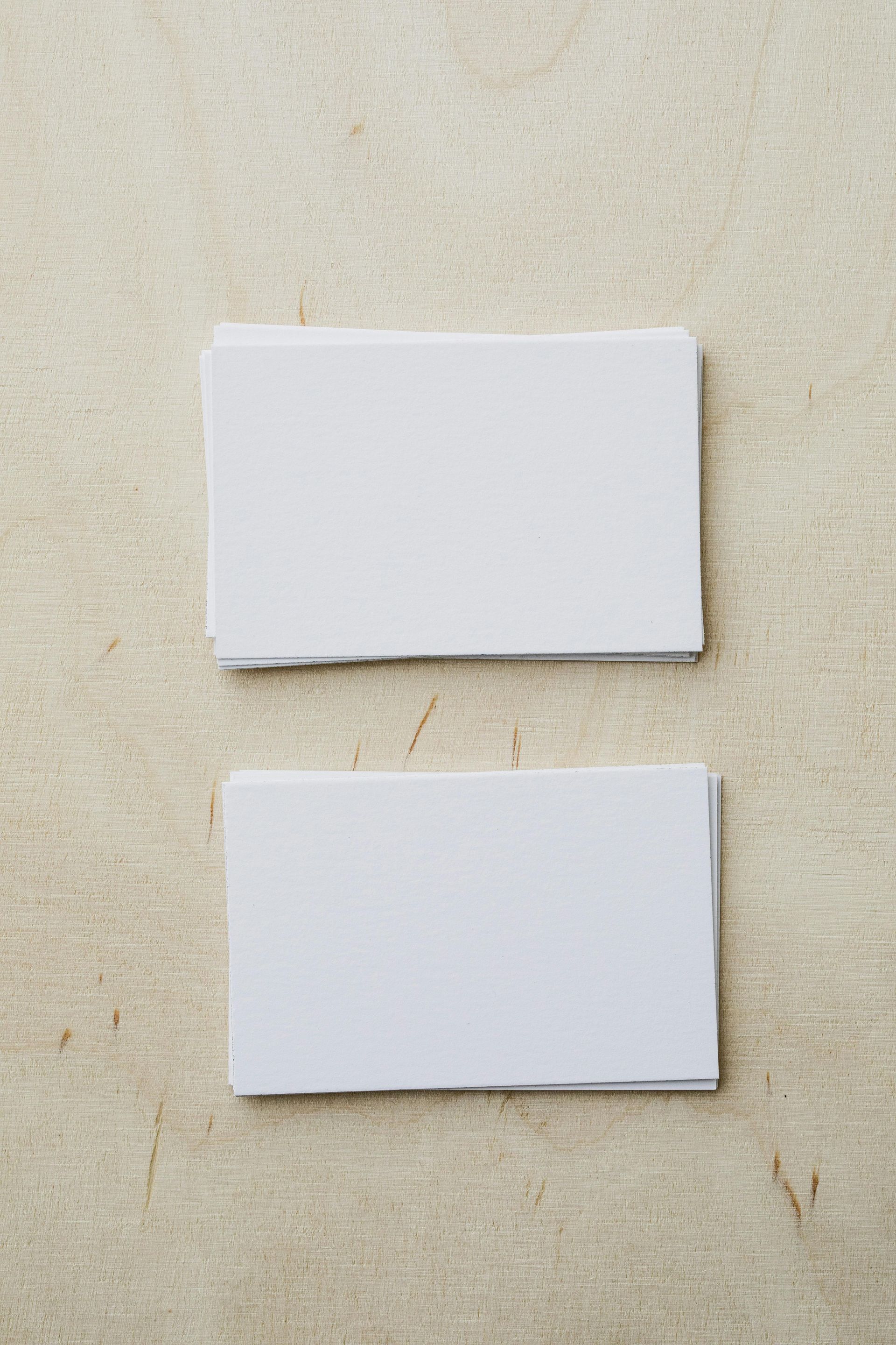 Two white business cards are stacked on top of each other on a table.