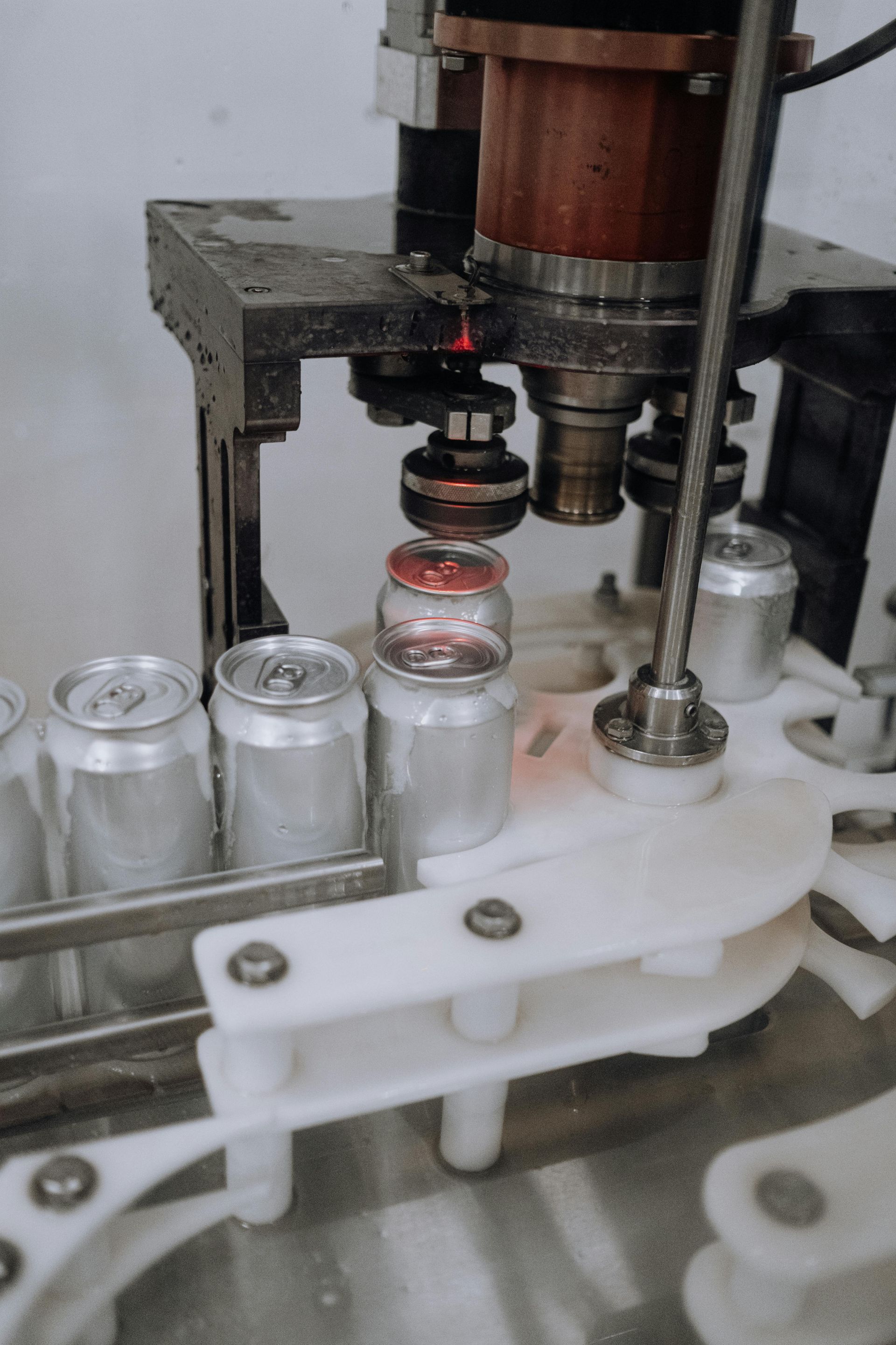 A machine is filling a can of soda with liquid