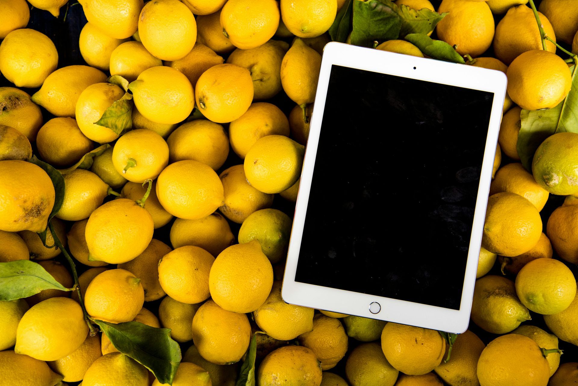 A tablet is sitting on top of a pile of lemons