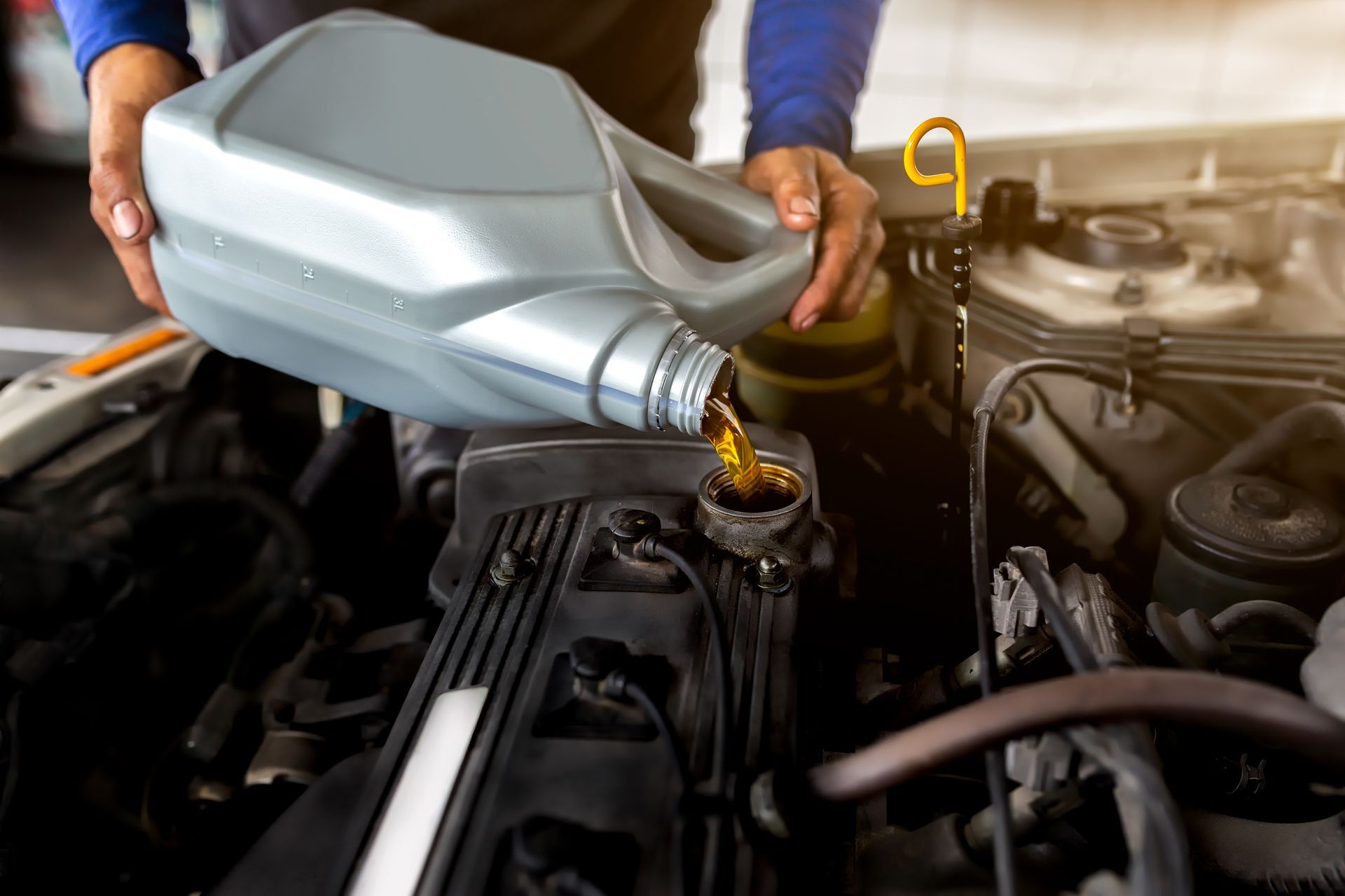 A man is pouring oil into a car engine.