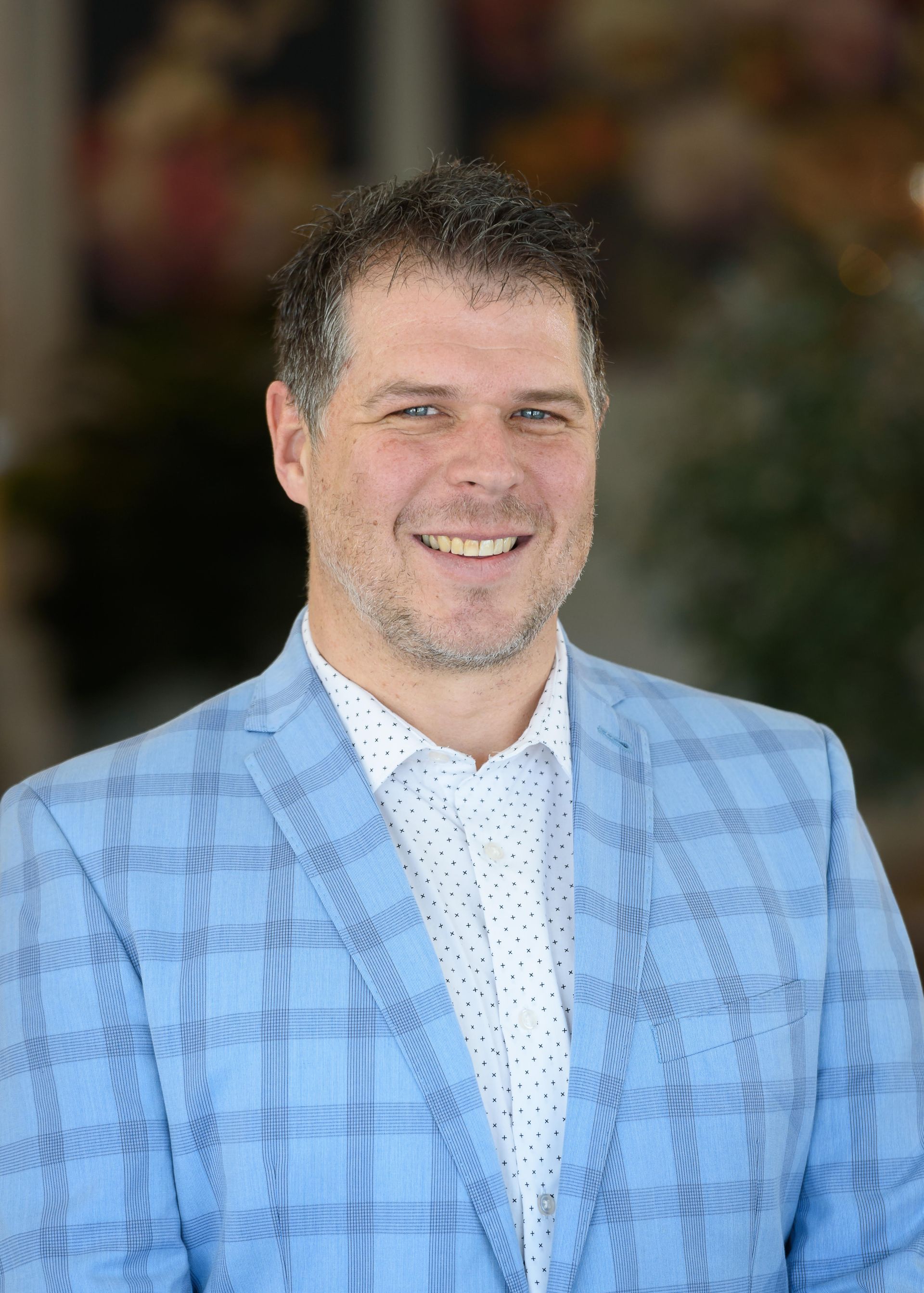 A man in a blue suit and white shirt is smiling for the camera.
