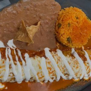 Enchilada covered in sauce and cream, served with rice, beans, and a tortilla chip.