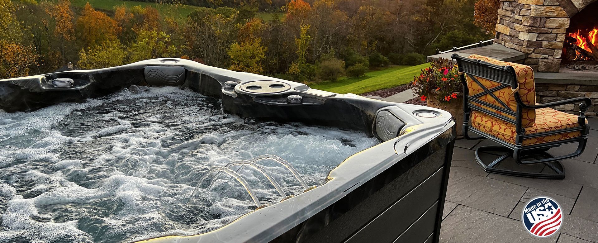 A hot tub is sitting on a patio next to a chair and a fireplace.