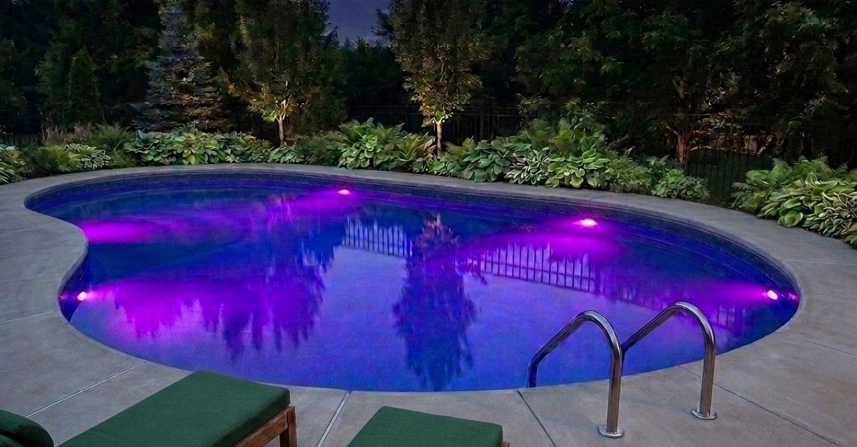 A swimming pool is lit up at night with purple lights.