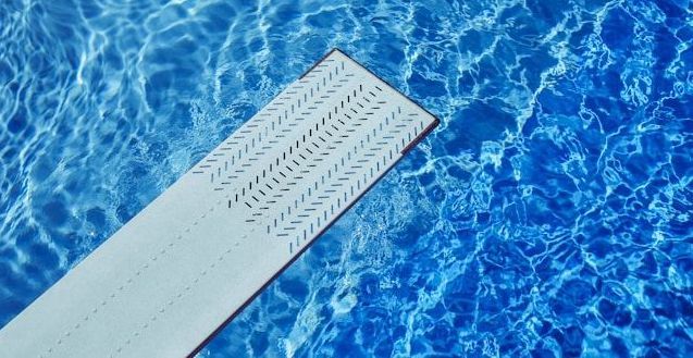 A diving board is in the middle of a swimming pool.