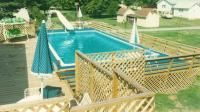 A large swimming pool with umbrellas and a slide in the backyard. homestead pool