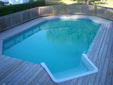 A large swimming pool surrounded by a wooden deck