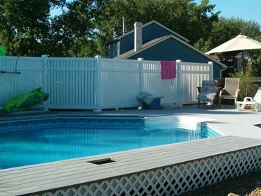 A white fence surrounds a large swimming pool