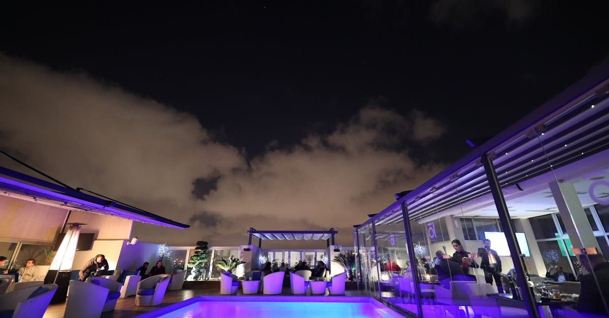 A swimming pool is lit up at night with purple lights.