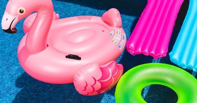 A pink flamingo float is sitting on top of a pool.