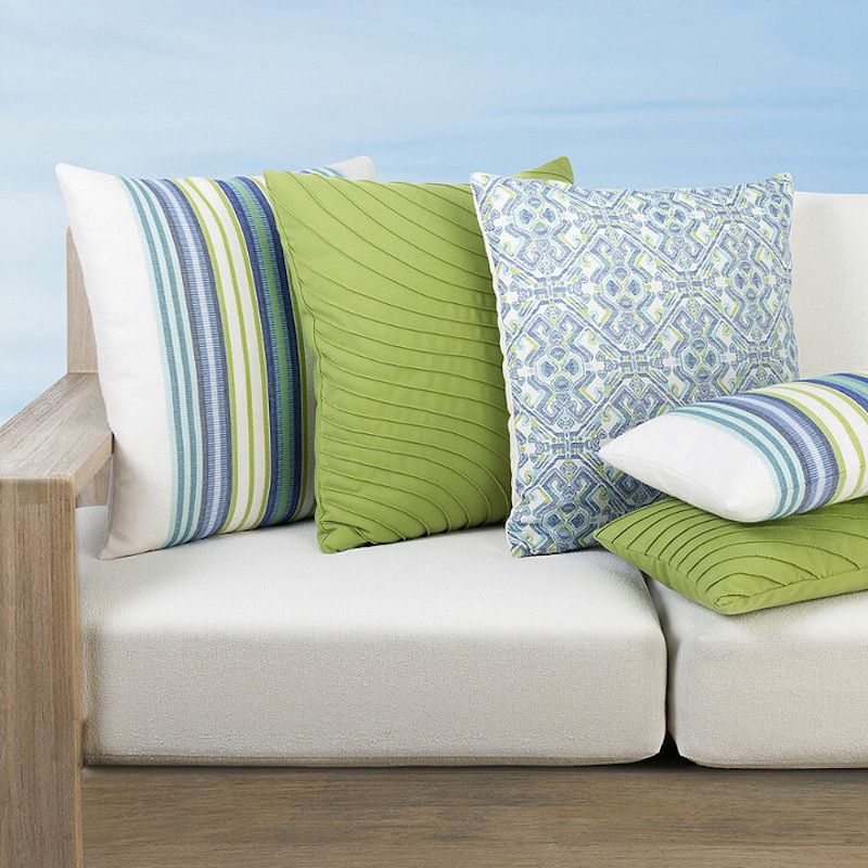 A white couch with green and blue pillows on it