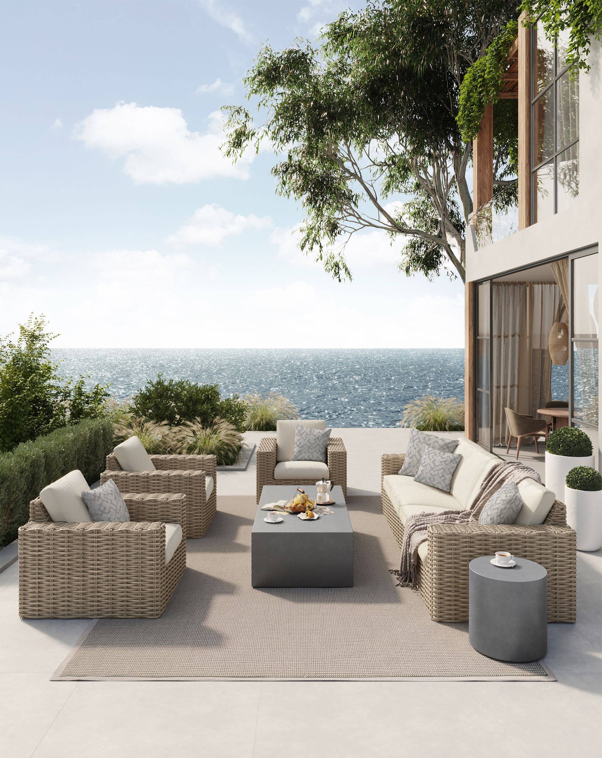 A patio with wicker furniture and a view of the ocean.