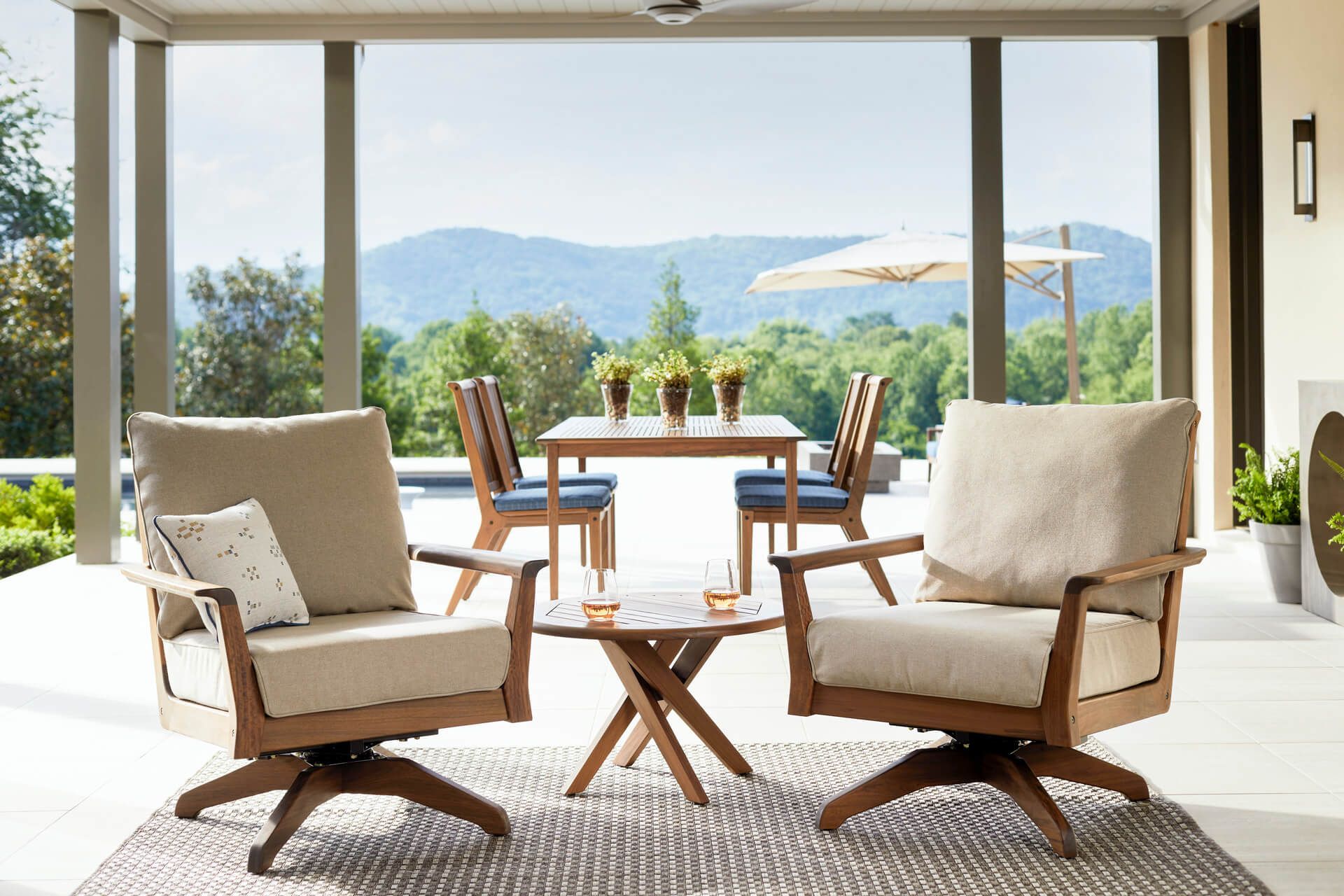 A patio with chairs and a table with a view of the mountains.
