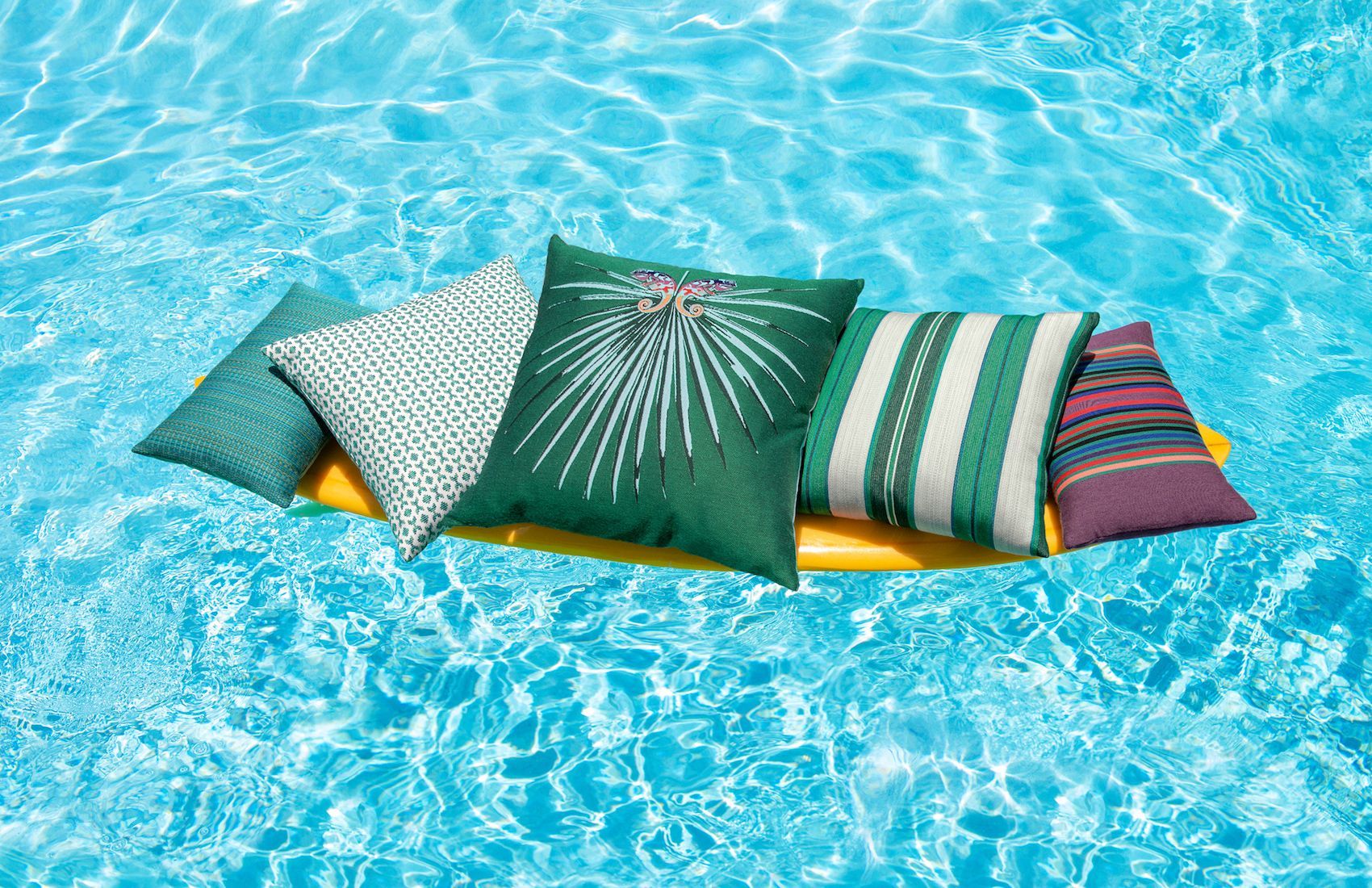 A bunch of pillows are floating in a swimming pool.
