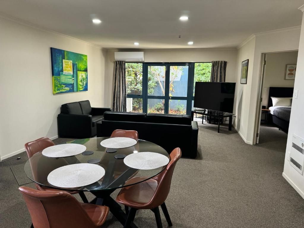 A hotel room with a bed , chair , table and nightstand.