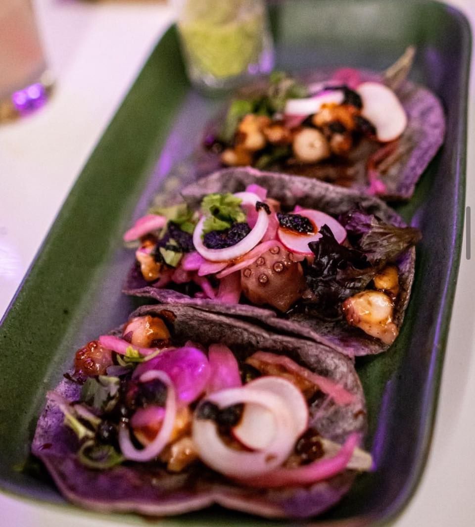 A tray of tacos with purple tortilla shells and vegetables