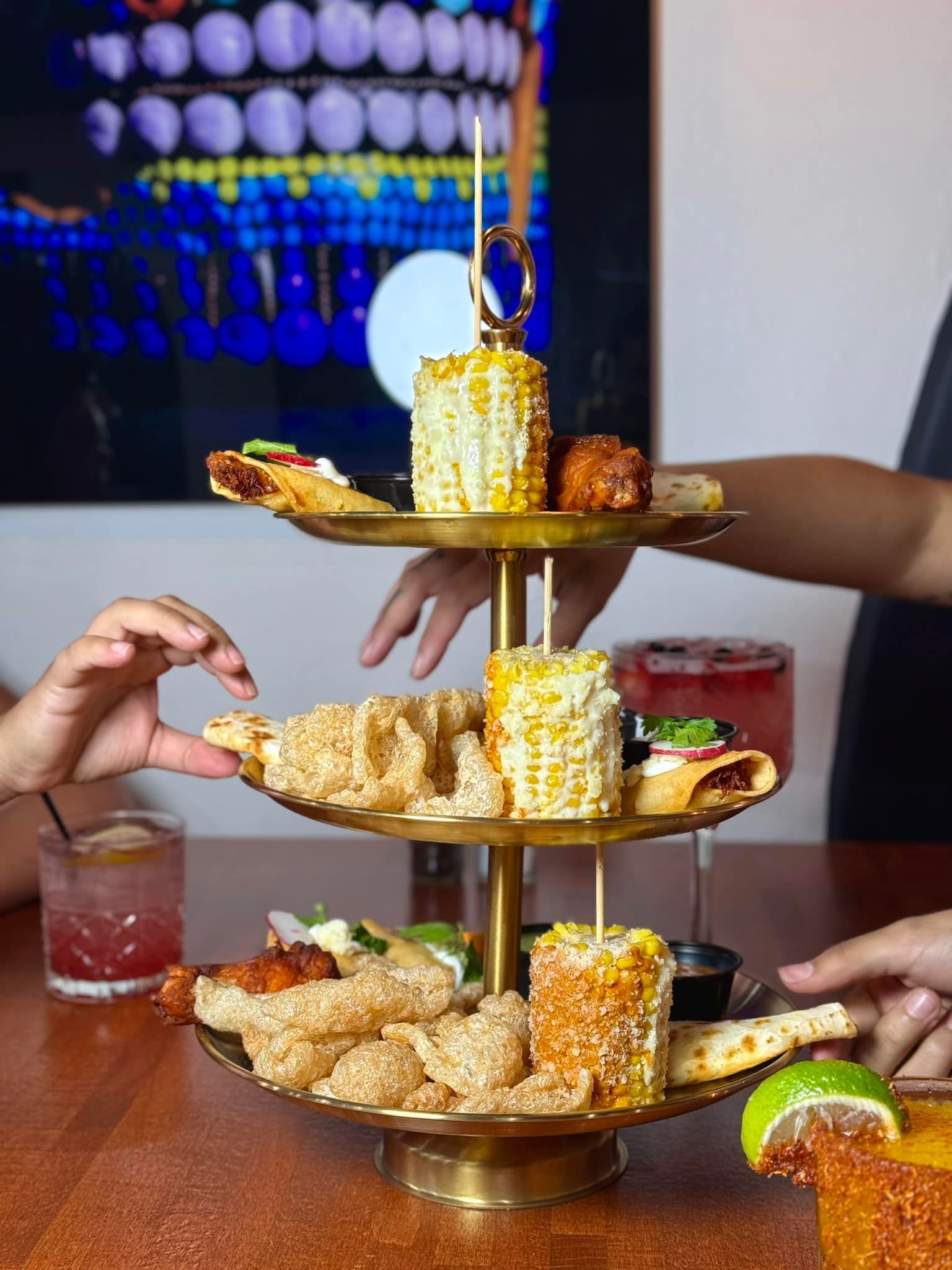 A three tiered tray filled with food and drinks on a table.