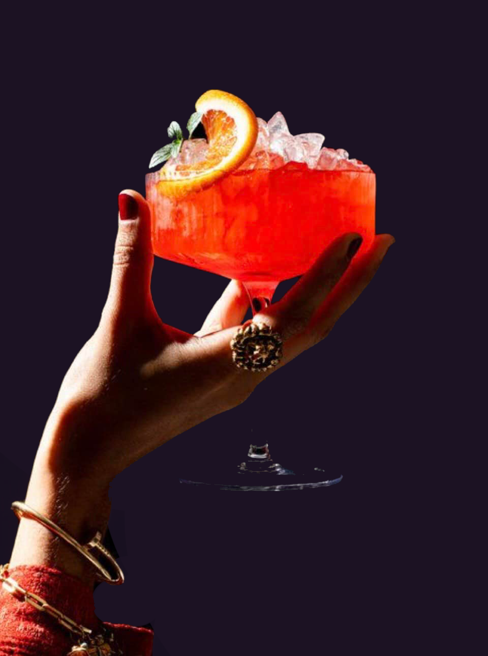 A woman is holding a red cocktail in her hand.