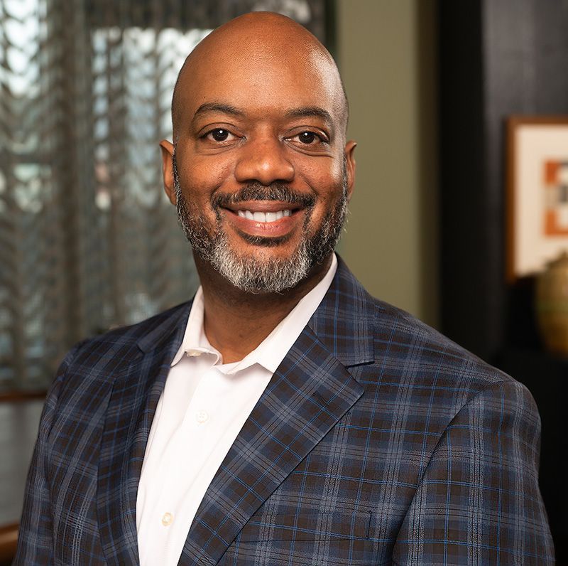 Bernard Williams n in a blue plaid blazer and white shirt, indoors.