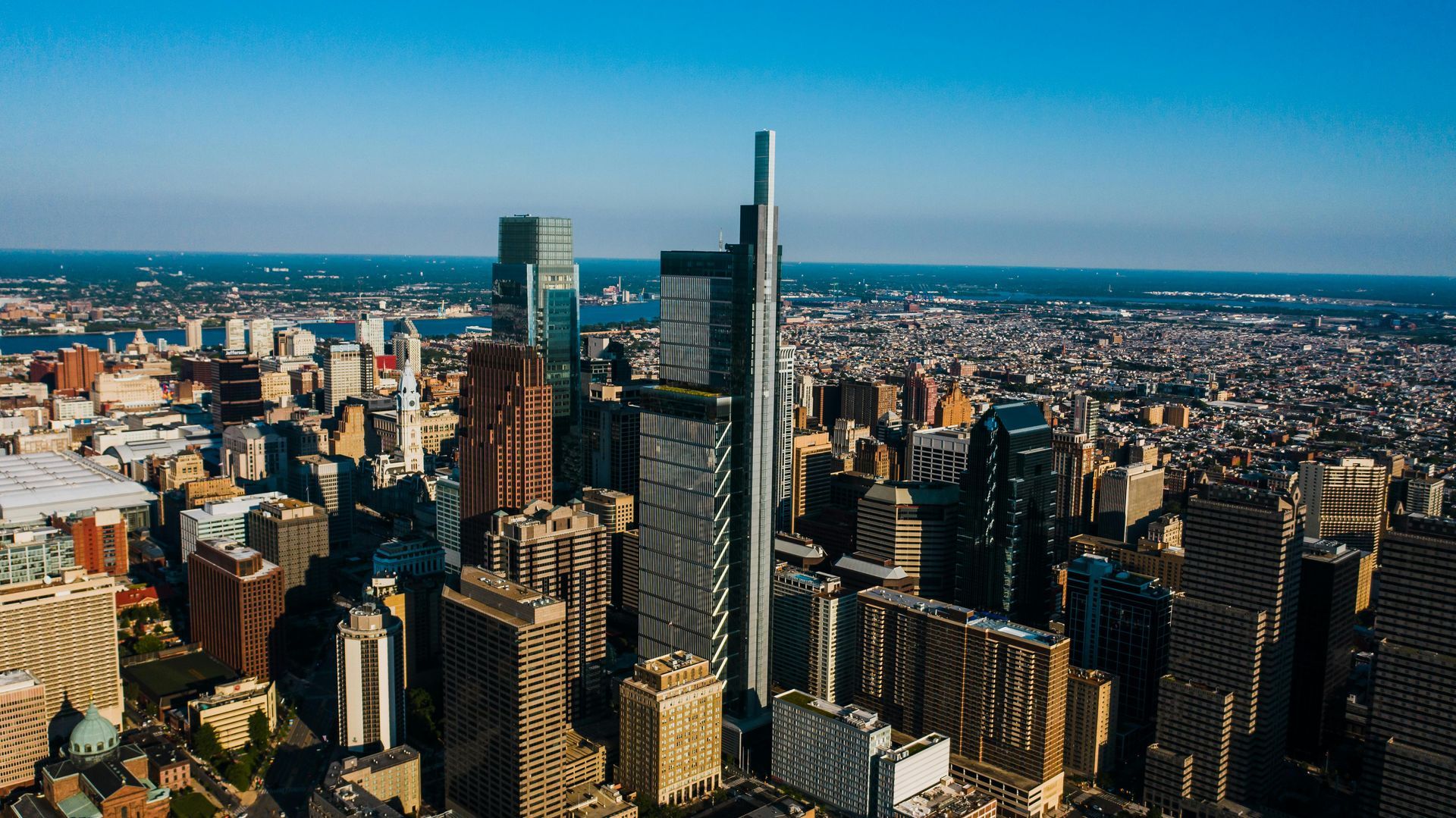 Aerial view of a dense downtown skyline with tall skyscrapers under a clear blue sky.