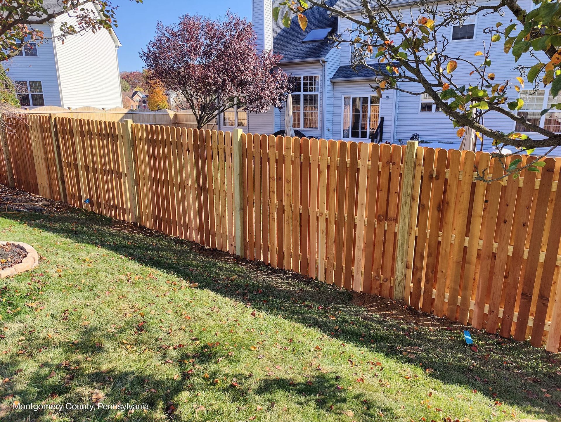 A wooden fence is in the backyard of a house.
