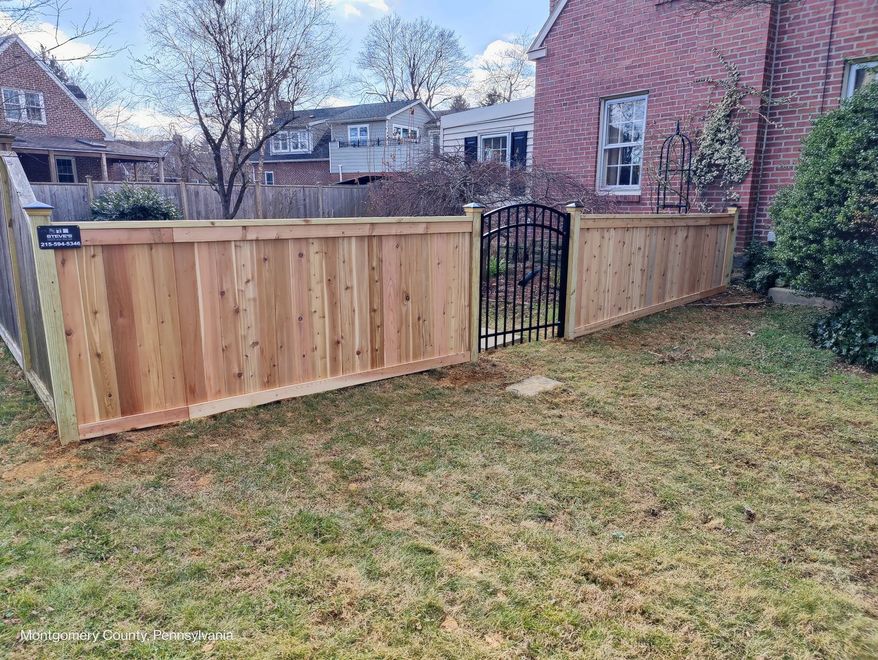 A wooden fence with a gate in the backyard of a house.