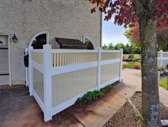 A white fence is sitting in front of a house.