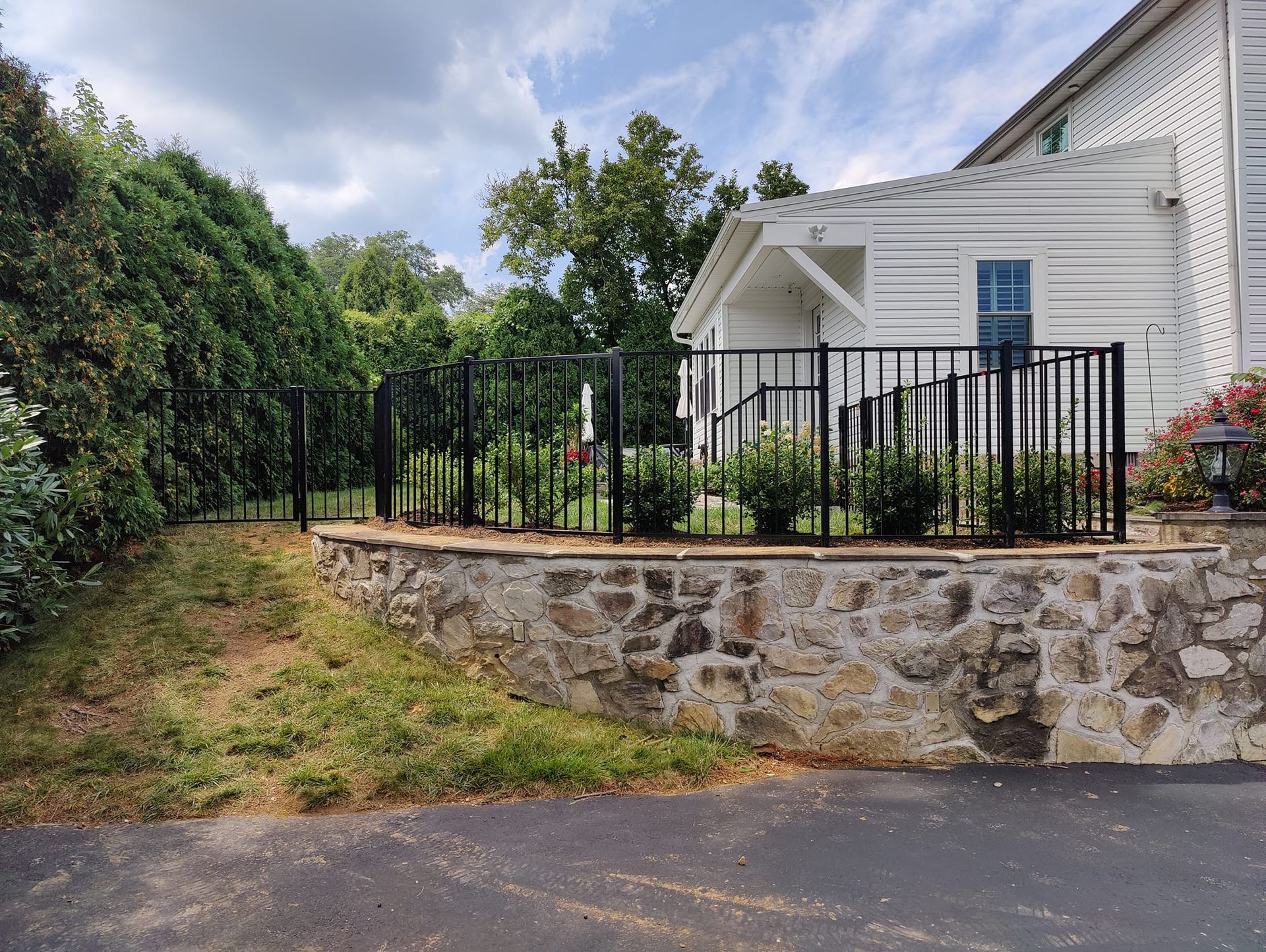 A white house with a black fence and a stone wall