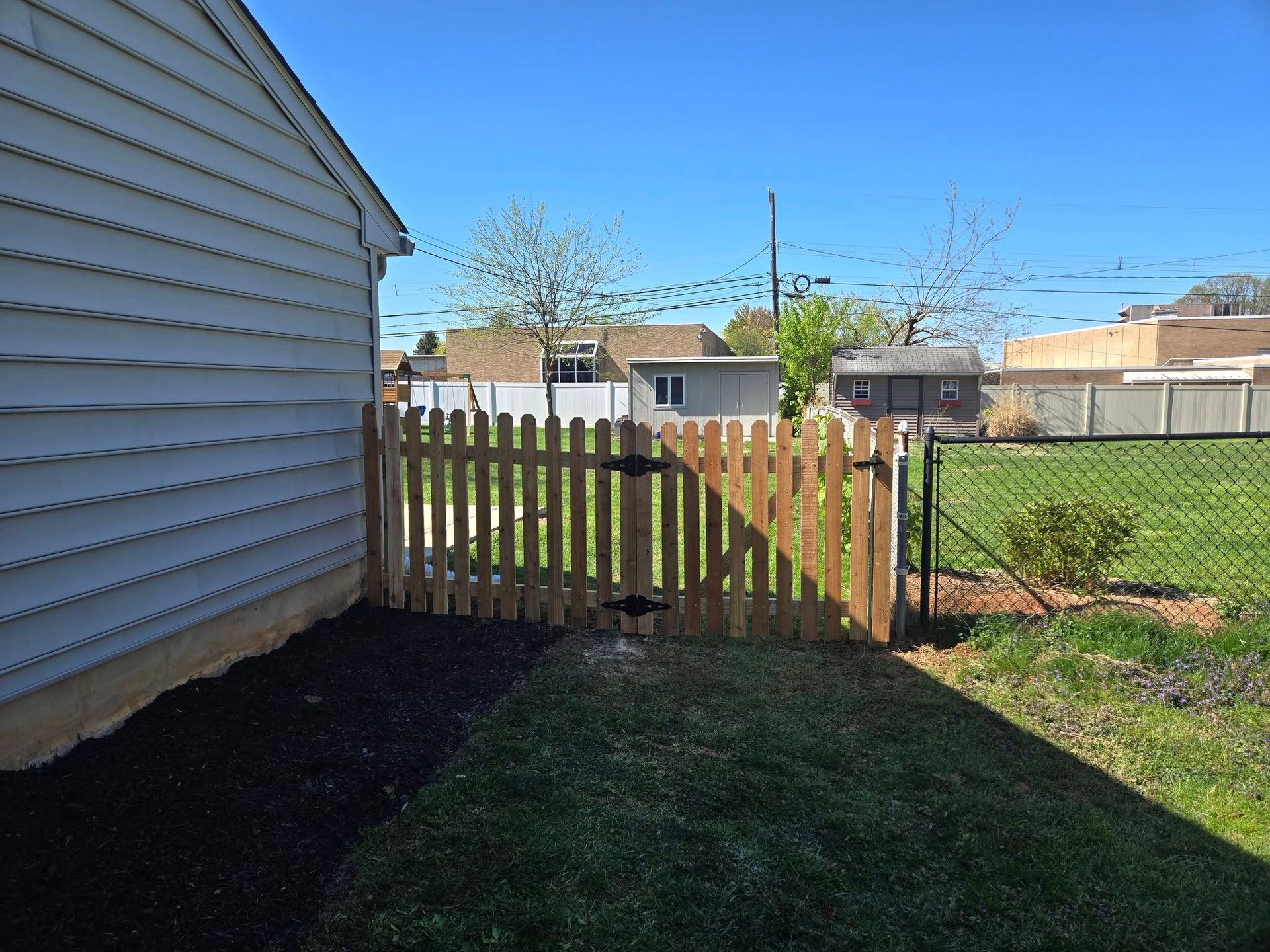 A backyard with a wooden fence and a chain link fence