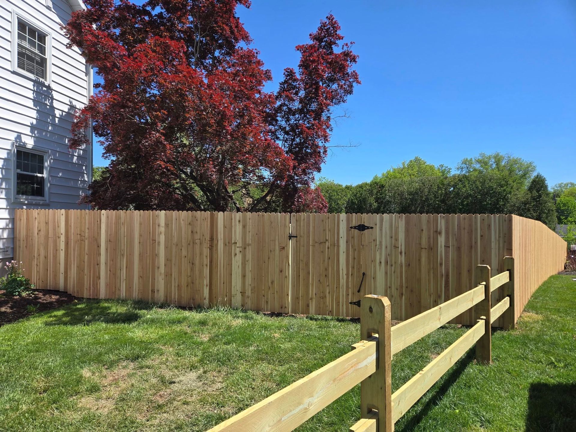 A wooden fence is in the backyard of a house.