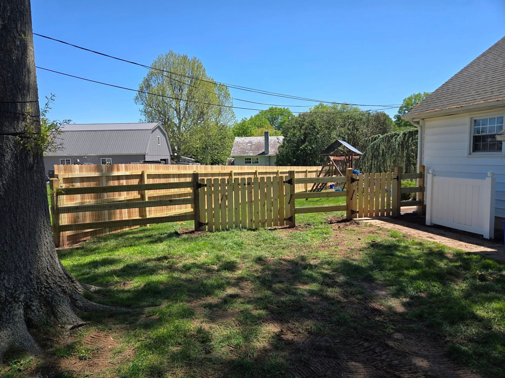 A wooden fence is in the backyard of a house.