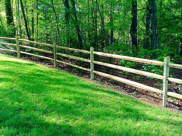 A wooden fence surrounds a lush green field.