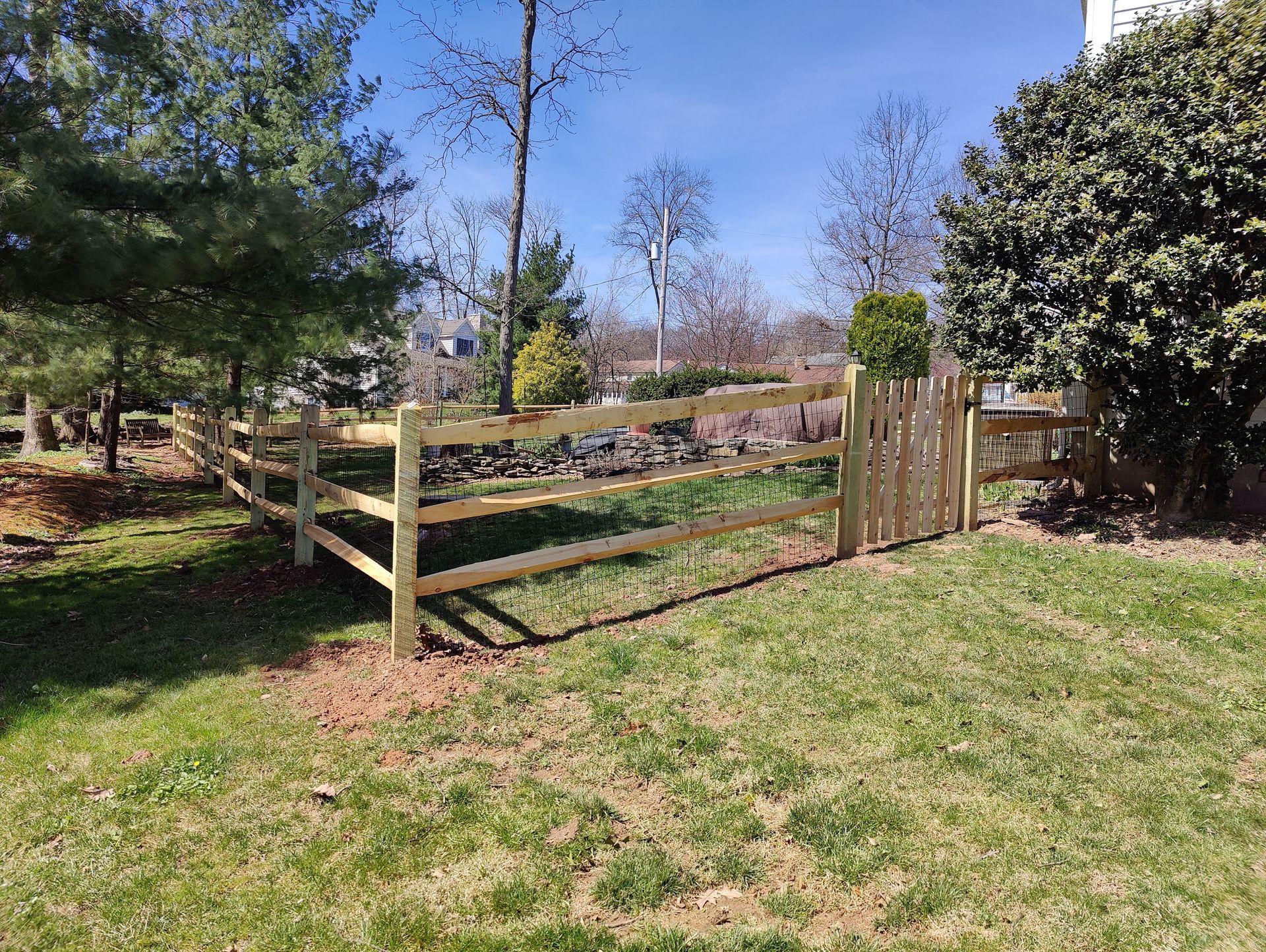 A wooden fence is in the middle of a lush green field.